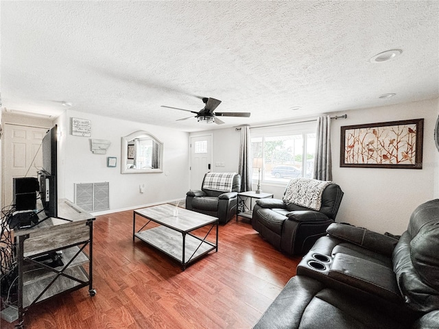 living room featuring a textured ceiling, wood finished floors, ceiling fan, and baseboards