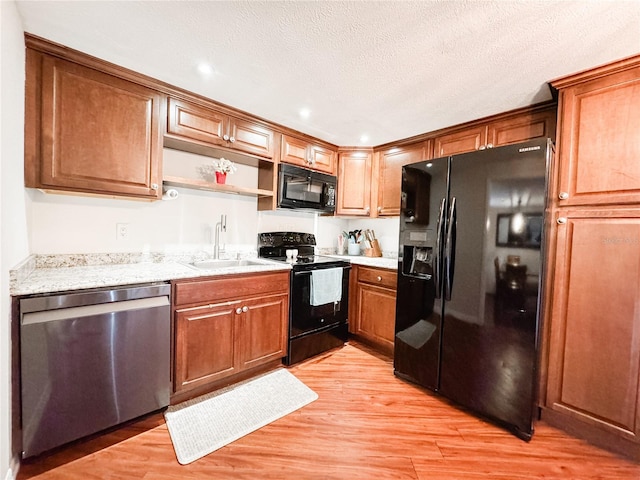 kitchen with black appliances, a sink, light wood-type flooring, open shelves, and brown cabinets
