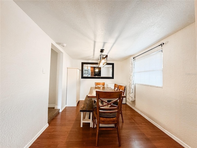 dining space with baseboards, wood finished floors, a textured ceiling, and a textured wall
