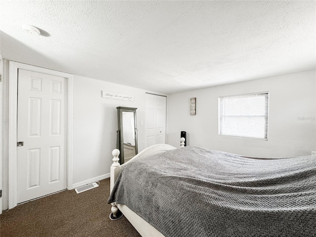 bedroom with a textured ceiling, dark colored carpet, and baseboards