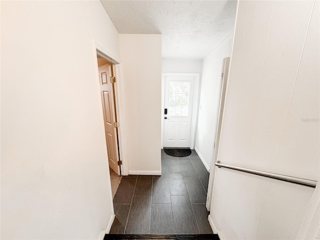 hallway featuring a textured ceiling, wood tiled floors, and baseboards