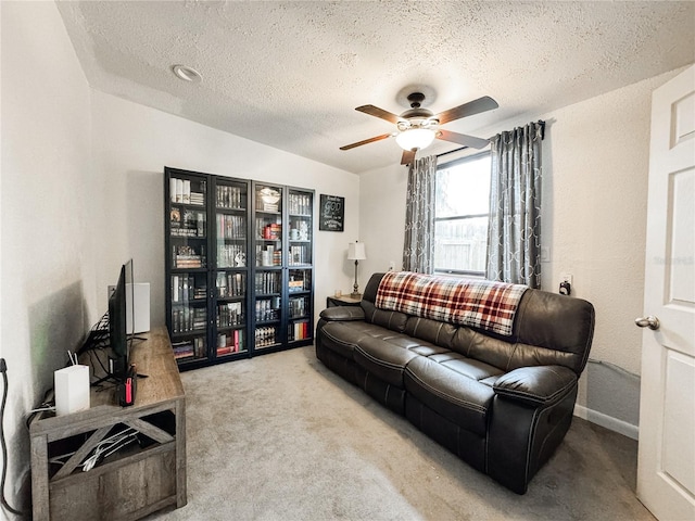 living room featuring a textured ceiling, carpet flooring, and ceiling fan