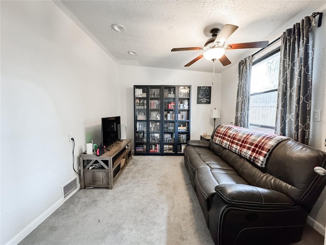 living area with ceiling fan, carpet, a textured ceiling, and baseboards