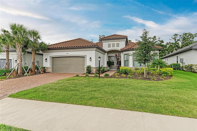 mediterranean / spanish home featuring decorative driveway, stucco siding, an attached garage, a tiled roof, and a front lawn