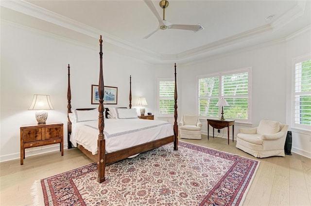 bedroom with crown molding, light wood-style floors, a tray ceiling, and ceiling fan
