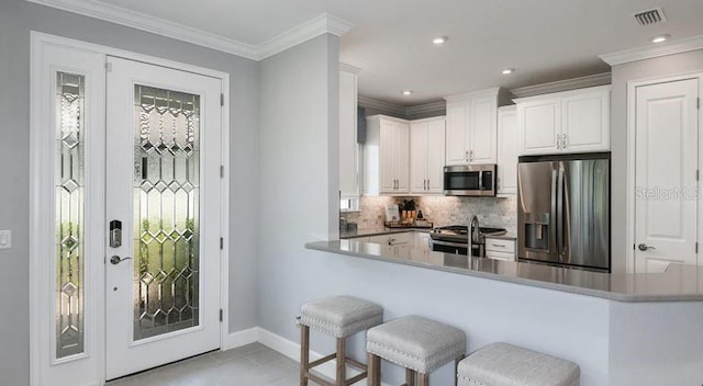 kitchen with appliances with stainless steel finishes, backsplash, baseboards, plenty of natural light, and ornamental molding