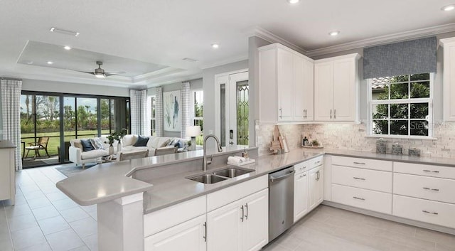 kitchen featuring stainless steel dishwasher, a sink, a peninsula, crown molding, and open floor plan