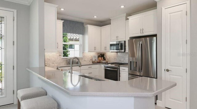 kitchen with stainless steel appliances, crown molding, white cabinetry, a peninsula, and a breakfast bar area