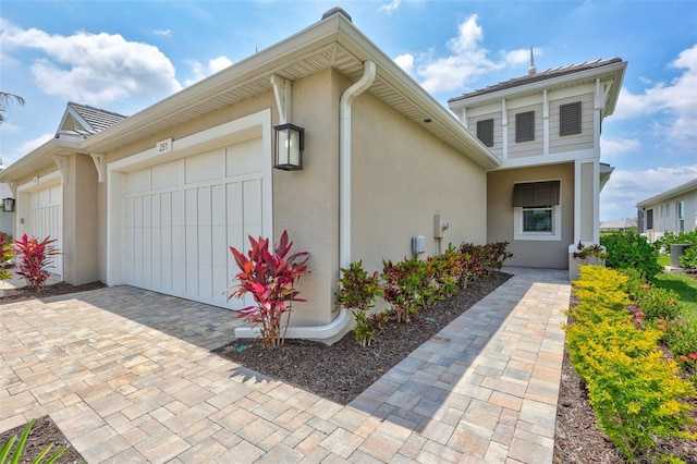 view of front facade with an attached garage, stucco siding, and decorative driveway