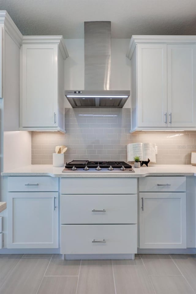 kitchen with range hood, stainless steel gas cooktop, white cabinets, and decorative backsplash