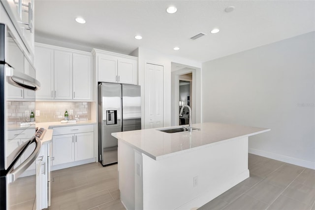 kitchen with stainless steel refrigerator with ice dispenser, a sink, backsplash, white cabinetry, and a kitchen island with sink