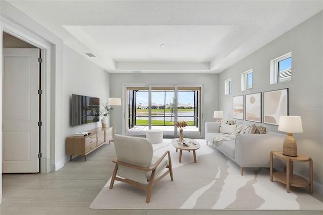 living area featuring a raised ceiling, baseboards, and light tile patterned floors
