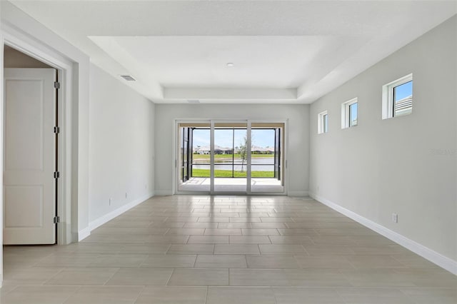 empty room featuring baseboards, a raised ceiling, and light tile patterned floors