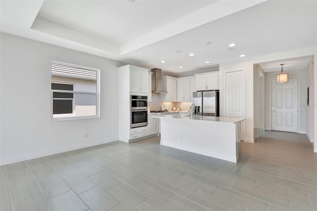kitchen with appliances with stainless steel finishes, wall chimney range hood, white cabinets, light countertops, and baseboards