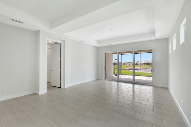 empty room featuring a tray ceiling and baseboards