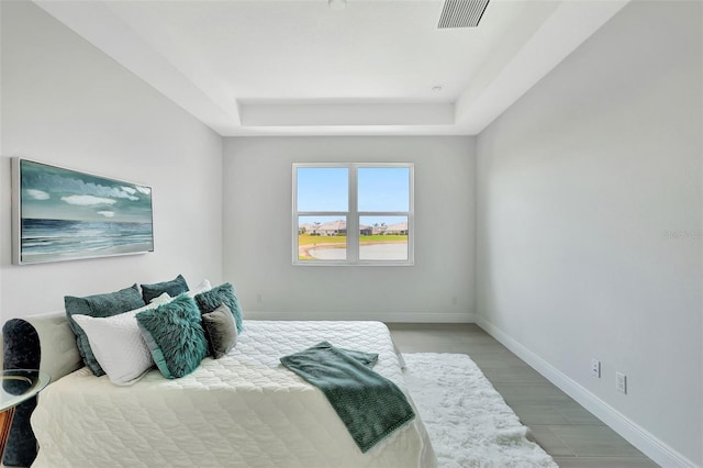 bedroom featuring a raised ceiling and baseboards