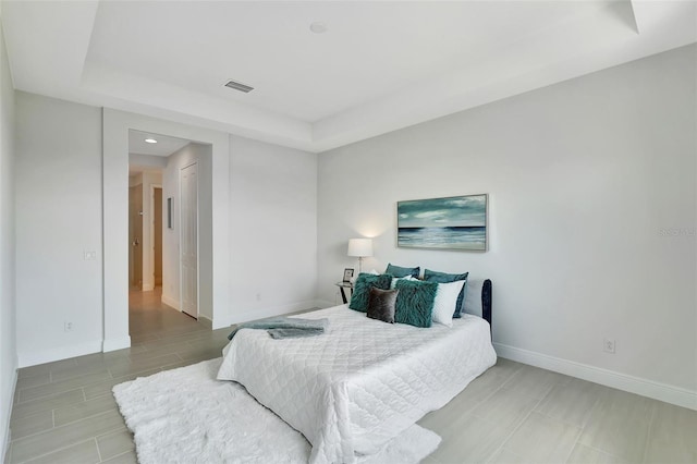 bedroom with a raised ceiling, baseboards, and recessed lighting