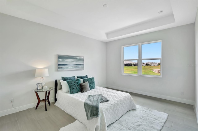 bedroom with baseboards and a raised ceiling