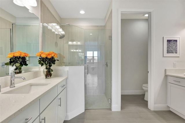 bathroom with tile patterned flooring, a shower stall, vanity, and baseboards