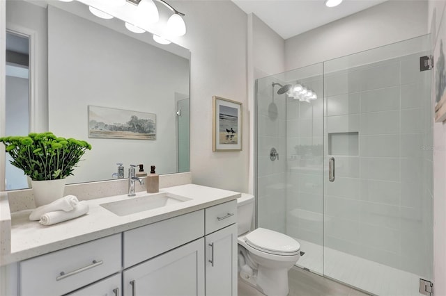 bathroom featuring a shower stall, toilet, and vanity