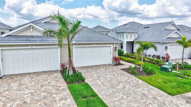 view of front facade with stucco siding, an attached garage, decorative driveway, and a front yard