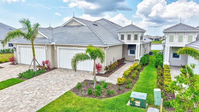view of front facade featuring stucco siding, an attached garage, driveway, a tile roof, and a front lawn