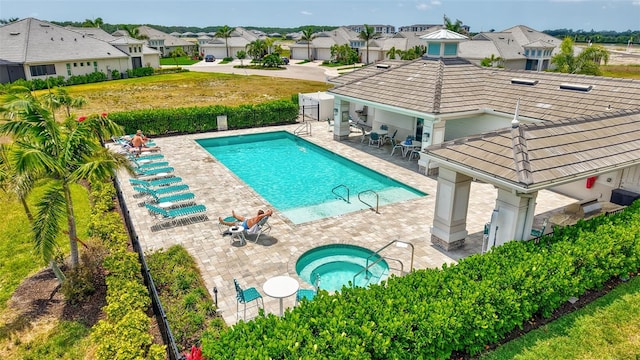 community pool featuring a community hot tub, a patio area, fence, and a residential view