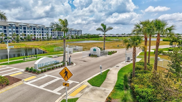 view of asphalt road featuring sidewalks, traffic signs, curbs, and a water view