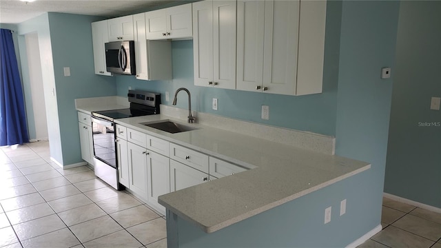 4304 78th St W Unit 4304, Bradenton, FL 34209 - kitchen with stainless steel appliances, a sink, light tile patterned flooring, white cabinetry, and baseboards