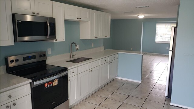 4304 78th St W Unit 4304, Bradenton, FL 34209 - kitchen featuring stainless steel appliances, a sink, light countertops, light tile patterned floors, and white cabinetry