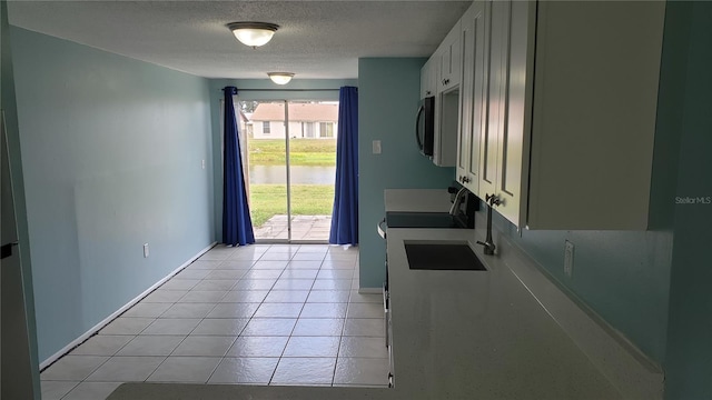 4304 78th St W Unit 4304, Bradenton, FL 34209 - kitchen with baseboards, a textured ceiling, light tile patterned flooring, stove, and white cabinets