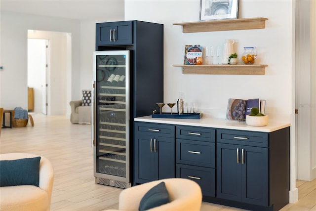 indoor dry bar with beverage cooler and light wood-style flooring
