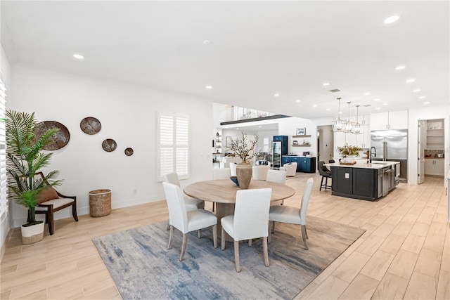 dining area featuring light wood finished floors, recessed lighting, baseboards, and a chandelier