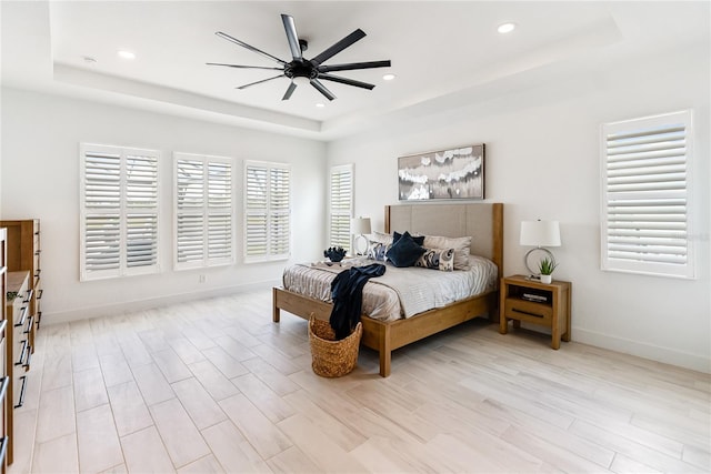 bedroom with a tray ceiling, recessed lighting, baseboards, ceiling fan, and light wood finished floors