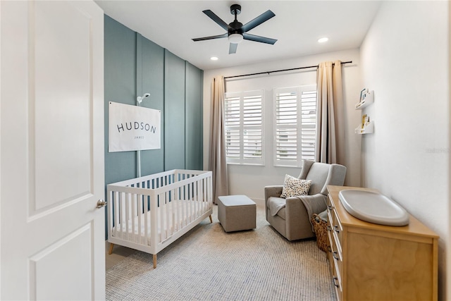 bedroom featuring a nursery area, recessed lighting, a ceiling fan, and light carpet