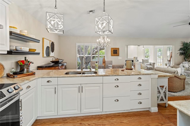 6402 23rd Avenue Dr W, Bradenton, FL 34209 - kitchen with a sink, stainless steel electric range, open floor plan, light wood finished floors, and white cabinetry