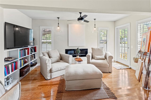 6402 23rd Avenue Dr W, Bradenton, FL 34209 - living area featuring light wood-type flooring, baseboards, a glass covered fireplace, and a ceiling fan