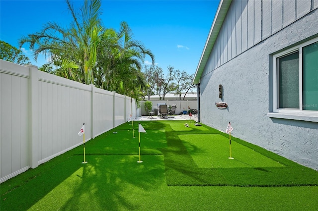 fenced backyard featuring a putting green and a patio area