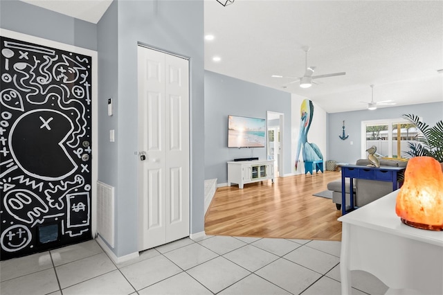 foyer featuring a ceiling fan, light tile patterned floors, and baseboards