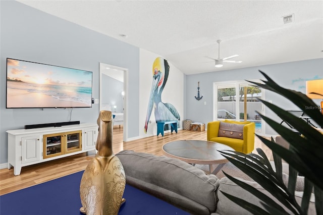 living area featuring a ceiling fan, wood finished floors, baseboards, and a textured ceiling
