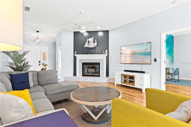 living room featuring wood finished floors, ceiling fan, and a high end fireplace