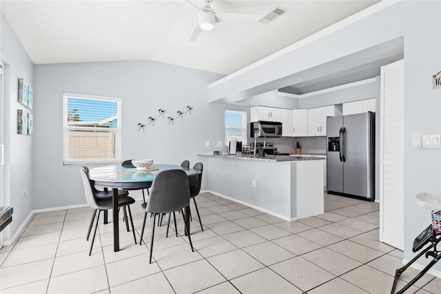 dining space with a ceiling fan, lofted ceiling, baseboards, and light tile patterned floors