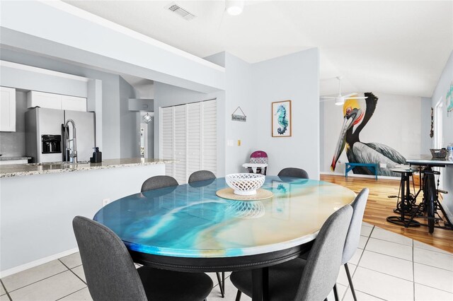dining area with light tile patterned floors and vaulted ceiling