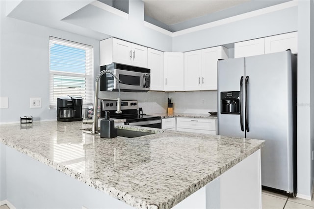 kitchen with stainless steel appliances, a peninsula, light stone counters, a sink, and white cabinets