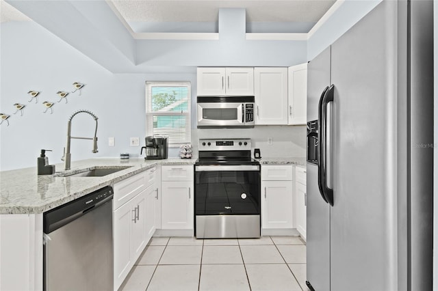 kitchen with stainless steel appliances, a sink, a peninsula, white cabinetry, and light tile patterned flooring