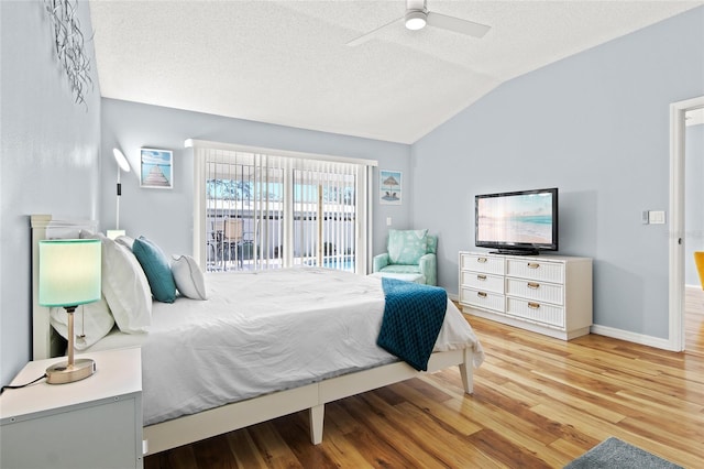 bedroom featuring lofted ceiling, access to exterior, a textured ceiling, wood finished floors, and ceiling fan