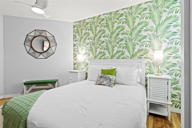bedroom with wallpapered walls, baseboards, wood finished floors, and a textured ceiling