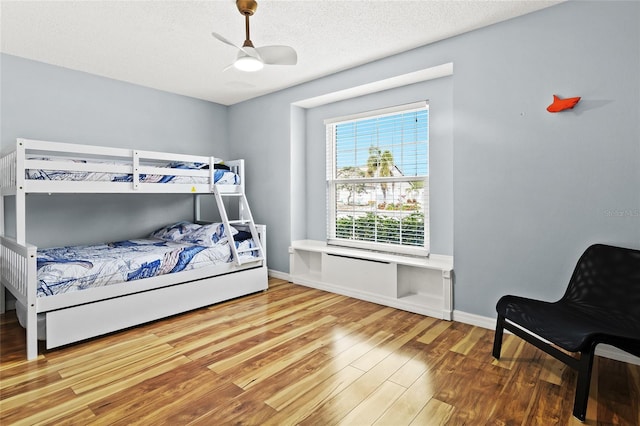 bedroom featuring wood finished floors, a ceiling fan, a textured ceiling, and baseboards
