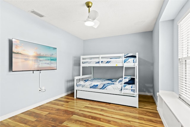 bedroom featuring wood finished floors, baseboards, a ceiling fan, and a textured ceiling