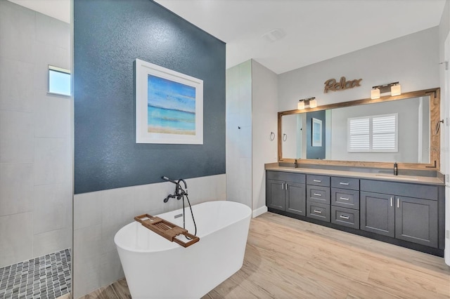 4312 Vasco St, Punta Gorda, FL 33950 - bathroom with wood finished floors, a freestanding tub, double vanity, walk in shower, and tile walls